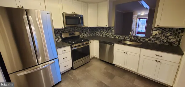 a kitchen with granite countertop stainless steel appliances a sink a counter space and cabinets