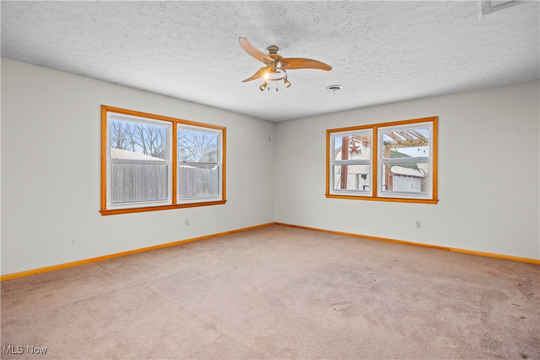 14015 West Lake Road Vermilion, OH 44089 - Photo 27 of 50 Unfurnished room featuring light carpet, ceiling fan, healthy amount of natural light, and a textured ceiling