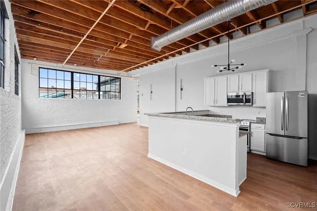 a view of a kitchen with refrigerator and wooden floor