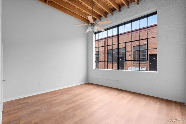 a view of an empty room with wooden floor and a window