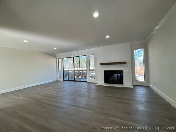 an empty room with wooden floor fireplace and windows