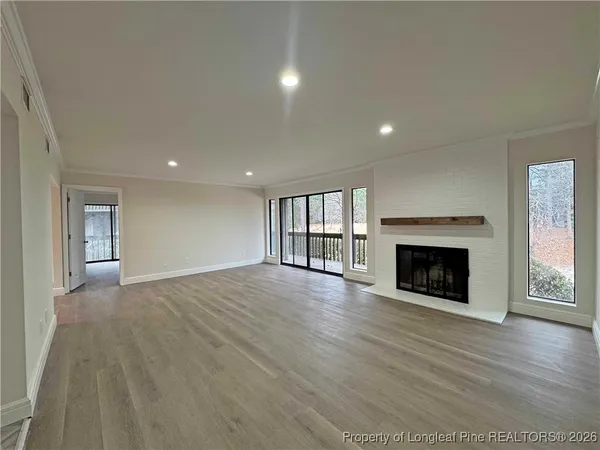 an empty room with wooden floor fireplace and windows