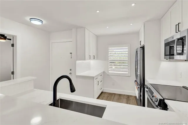 an empty room with wooden floor cabinet and windows