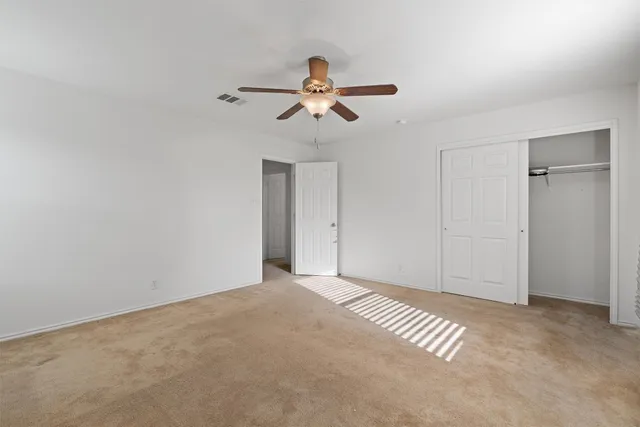 a view of a room with a ceiling fan and carpet