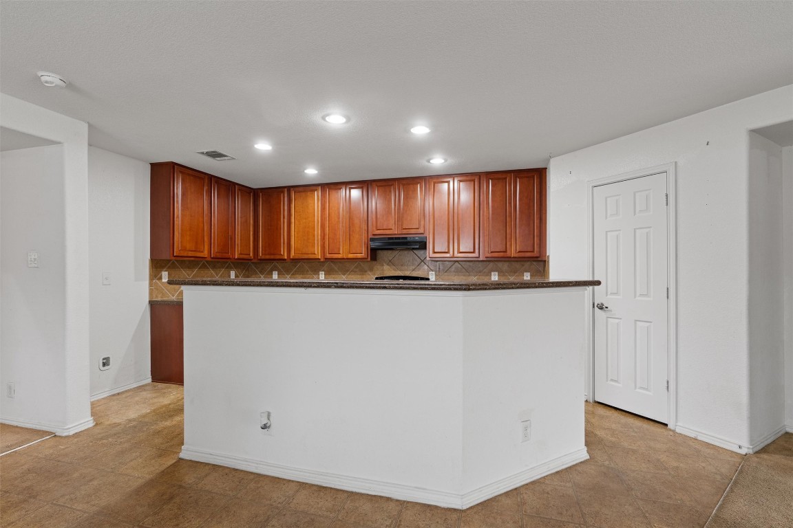 5700 Welsh Way Del Valle, TX 78617 - Photo 8 of 39 a kitchen with granite countertop wooden cabinets and a refrigerator