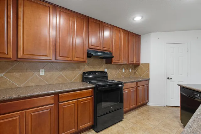 a kitchen with granite countertop stainless steel appliances wooden cabinets and a sink