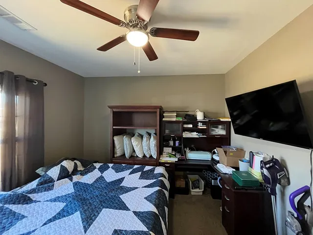 a bedroom with furniture or flat screen tv and a ceiling fan