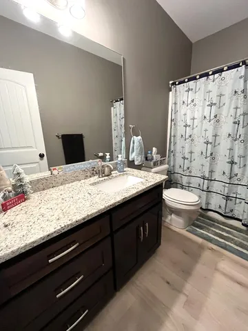 a bathroom with a granite countertop double vanity sink toilet and shower