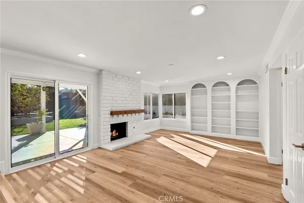 a view of a livingroom with wooden floor a fireplace and window
