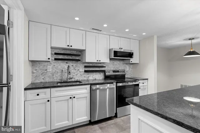 a kitchen with granite countertop white cabinets and stainless steel appliances