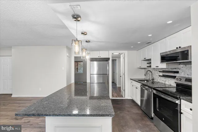 a kitchen with stainless steel appliances granite countertop a refrigerator a stove and a sink