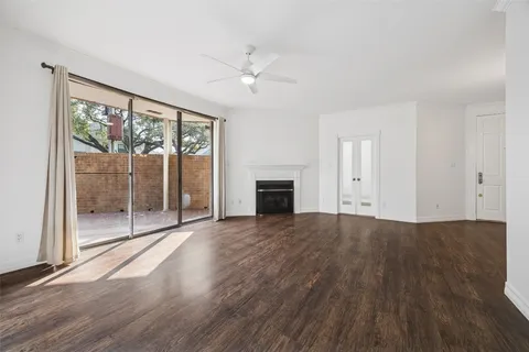 an empty room with wooden floor fireplace and windows