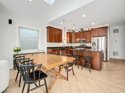 a kitchen with stainless steel appliances kitchen island granite countertop a table chairs and a refrigerator