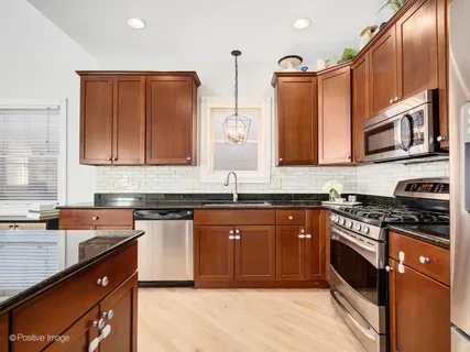 a kitchen with stainless steel appliances granite countertop wooden cabinets a stove top oven a sink and dishwasher