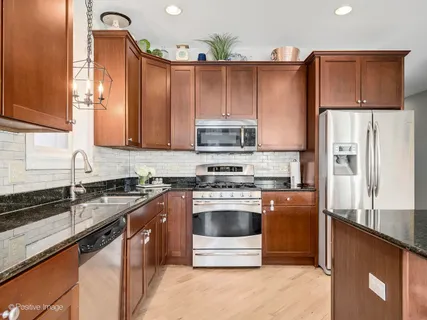 a kitchen with granite countertop a refrigerator stove and sink