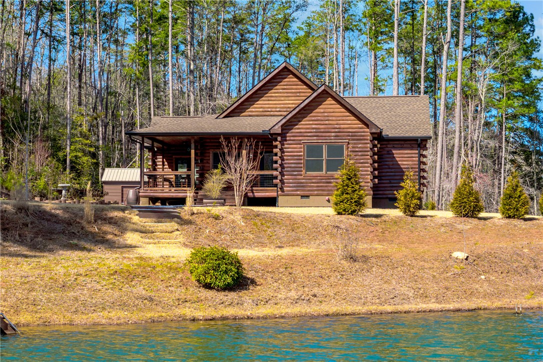 This tranquil lakefront cabin offers serene living with natural wood siding and a welcoming porch.