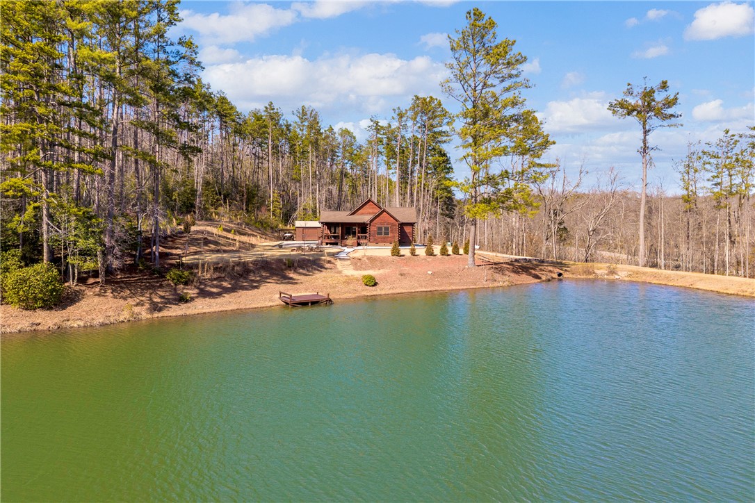 239 North Little River Road Salem, SC 29676 - Photo 43 of 43 Escape to this rustic retreat, featuring a charming cabin nestled beside a serene pond, embraced by lush trees.