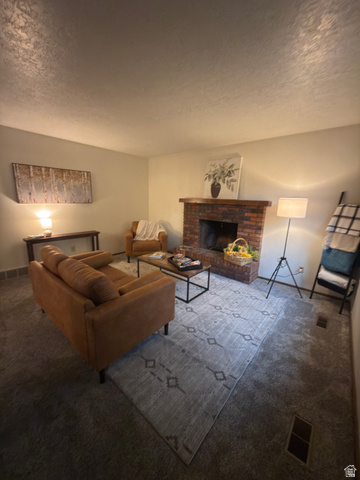 1164 East Mountain Road Logan, UT 84321 - Photo 29 of 45 Living area featuring a brick fireplace with a wood mantle, neutral wall colors, and carpet flooring