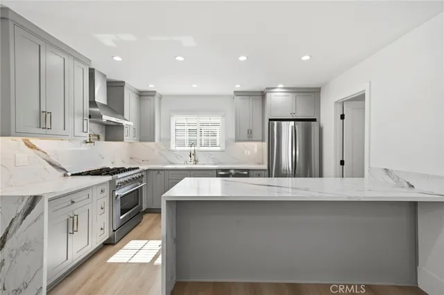 a large kitchen with stainless steel appliances granite countertop a lot of counter space and wooden floors