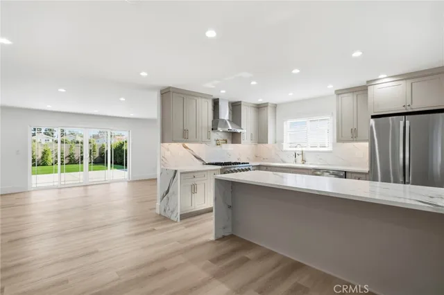 a kitchen with stainless steel appliances granite countertop a sink a stove a refrigerator and island with wooden floor