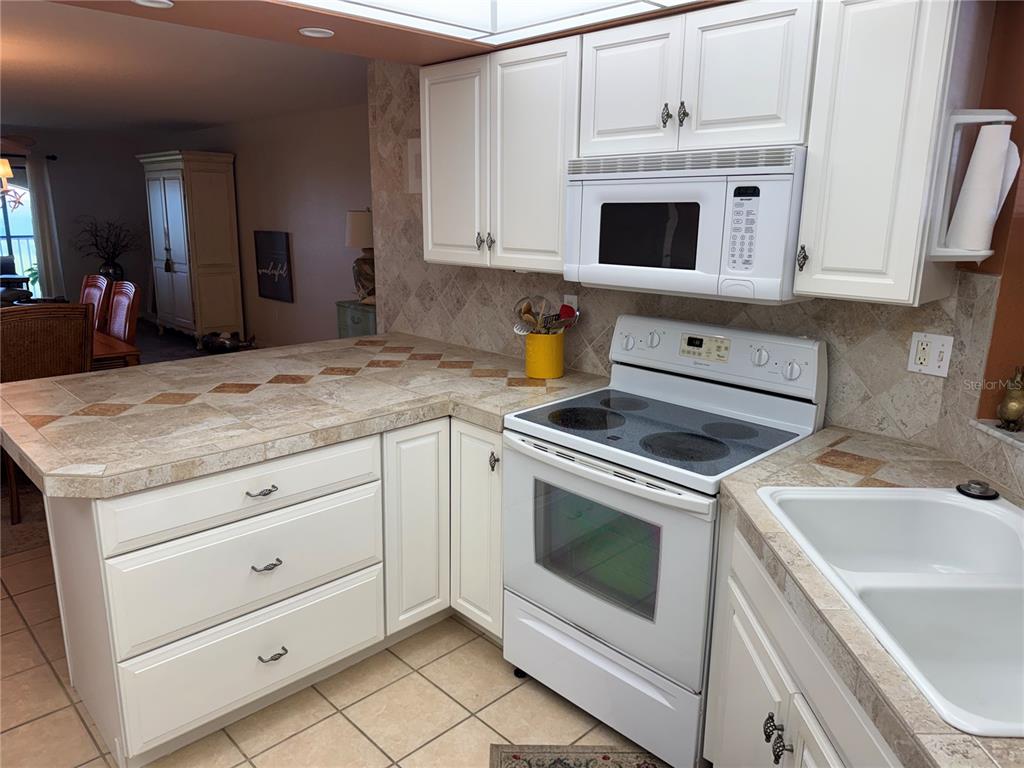 23465 Harbor View Road, Unit 244 Punta Gorda, FL 33980 - Photo 8 of 61 a kitchen with granite countertop white cabinets stainless steel appliances and sink
