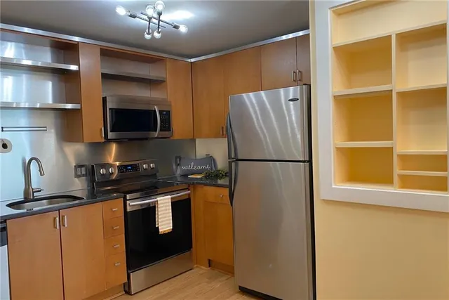a kitchen with stainless steel appliances granite countertop a refrigerator a stove top oven a sink and dishwasher