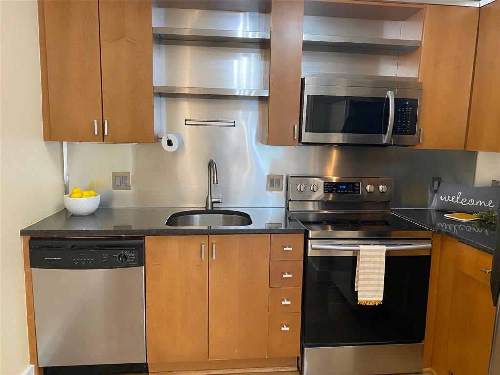 181 Powell Street Southeast, Unit 2 Atlanta, GA 30316 - Photo 9 of 47 a kitchen with stainless steel appliances granite countertop a stove a microwave and wooden cabinets