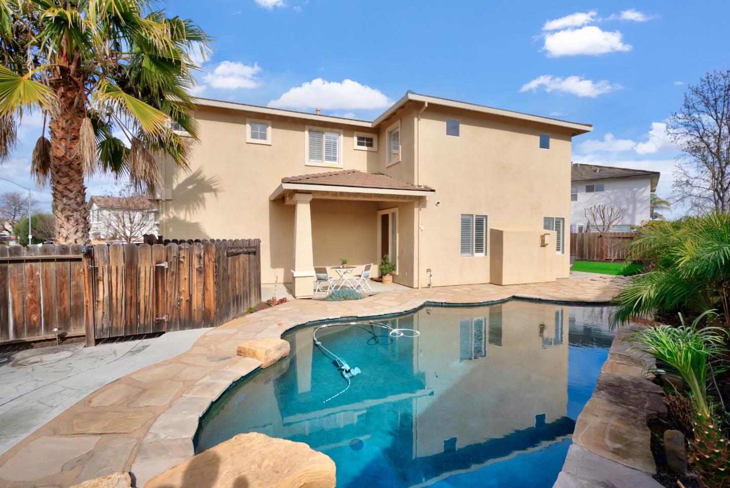 8850 Morey Way Gilroy, CA 95020 - Photo 27 of 34 a view of a white house with swimming pool lawn chairs and a barbeque
