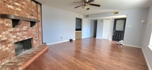 a view of an empty room with wooden floor fireplace and a window