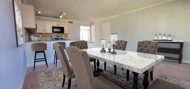 a open kitchen with stainless steel appliances kitchen island granite countertop a stove a sink a dining table and chairs