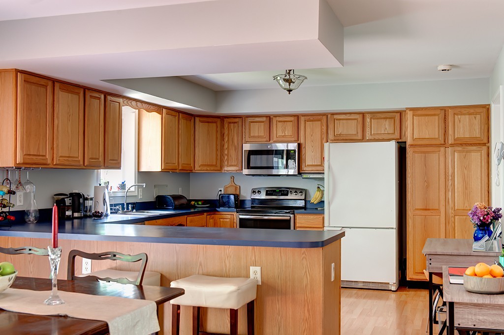 64 Farm Pond Road Oakham, MA 01068 - Photo 7 of 20 a kitchen with stainless steel appliances granite countertop a refrigerator a stove top oven a sink a dining table and chairs with the large windows