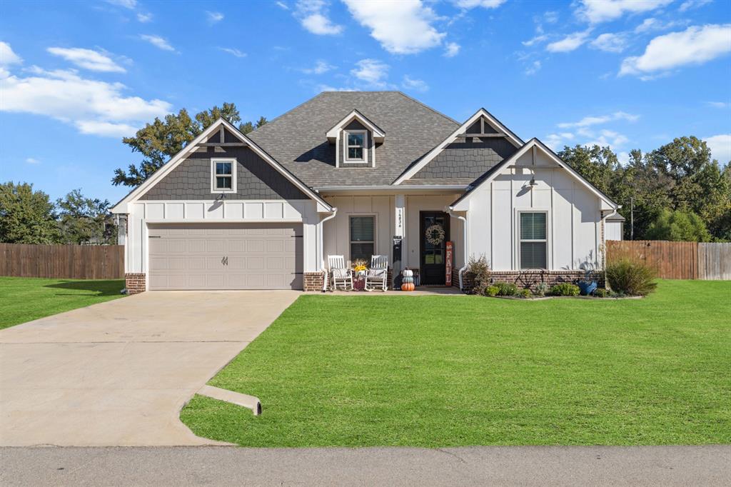 View of front facade with board and batten siding, driveway, a shingled roof, and a garage