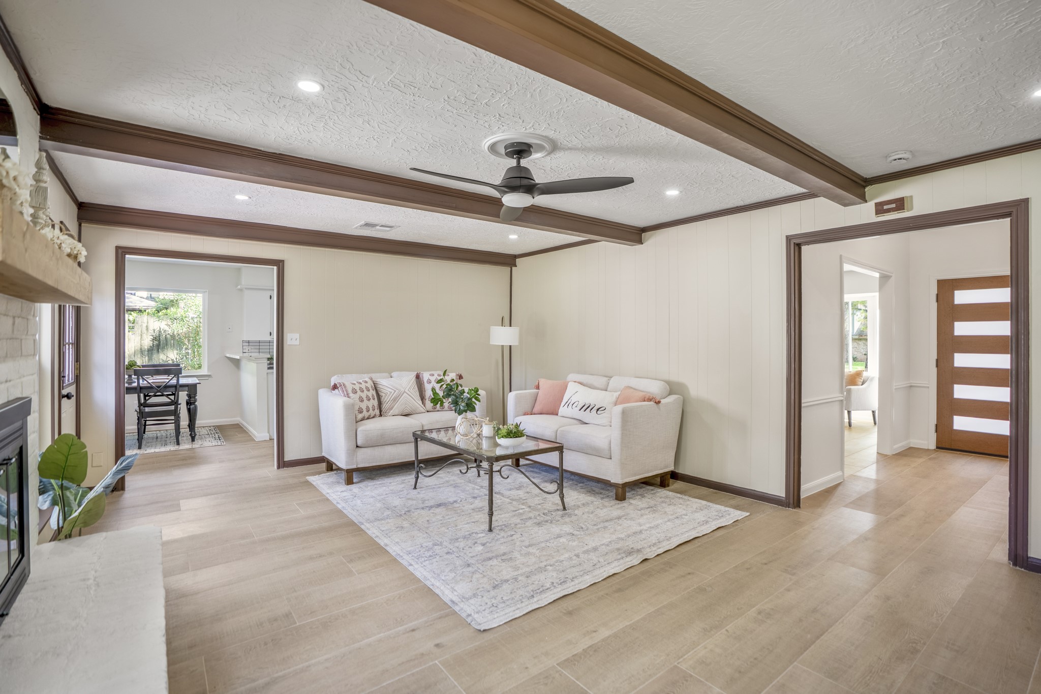 6303 Larkmount Drive Spring, TX 77389 - Photo 20 of 50 Turning back across the family room, the connected flow of the downstairs layout comes fully into view. The breakfast area and kitchen sit just beyond the opening to the left, while the foyer and front entry are visible through the doorway on the right. Between the wood-beamed ceiling, recessed lighting, updated flooring, and generous size of the room itself, the space feels designed for both comfortable nights in and larger gatherings when everyone ends up naturally gravitating here.