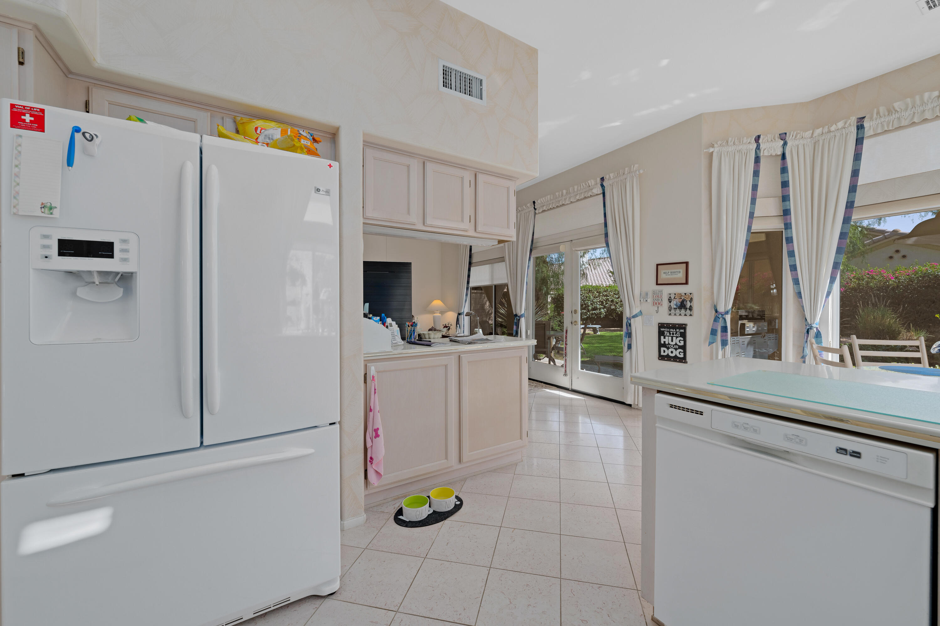78274 Rainbow Drive Palm Desert, CA 92211 - Photo 17 of 24 a kitchen with a refrigerator a stove and white cabinets with wooden floor