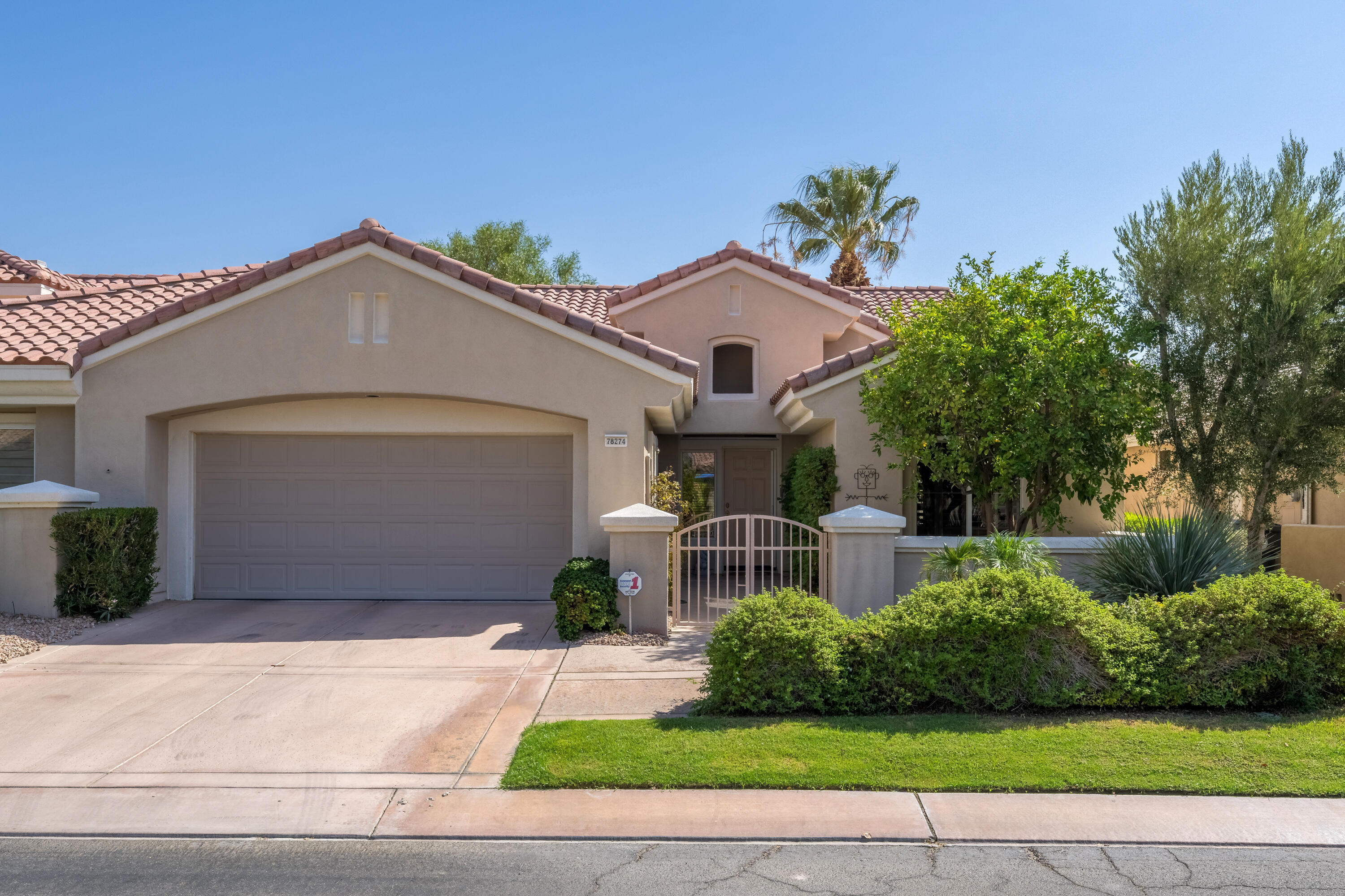78274 Rainbow Drive Palm Desert, CA 92211 - Photo 2 of 24 a front view of a house with a yard and garage