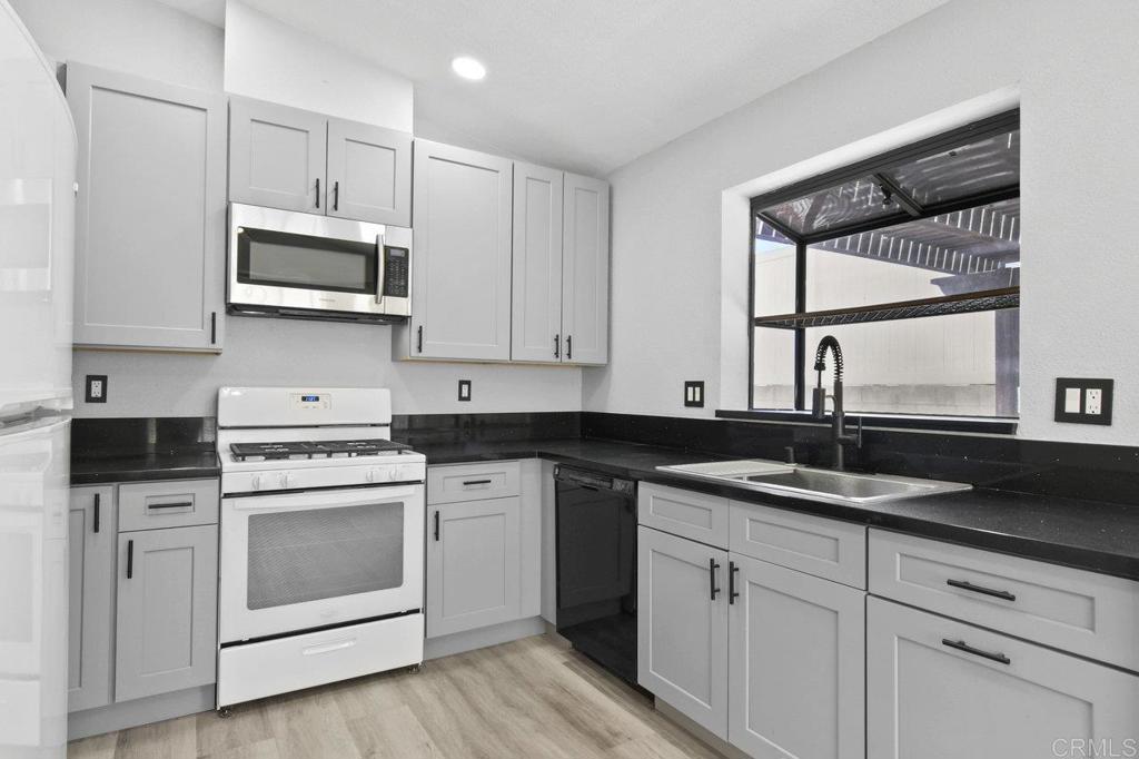 8409 Sleepy Way El Cajon, CA 92021 - Photo 9 of 31 a kitchen with granite countertop white cabinets and white appliances