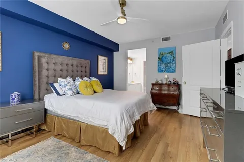 a bedroom with a bed dresser and a flat tv screen on dresser