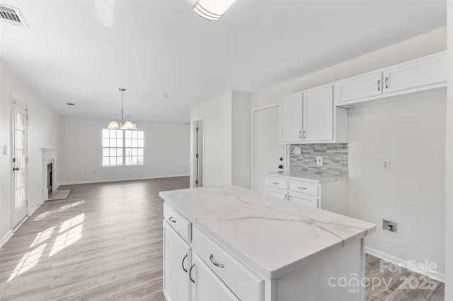 a kitchen with stainless steel appliances granite countertop a sink stove and white cabinets with wooden floor