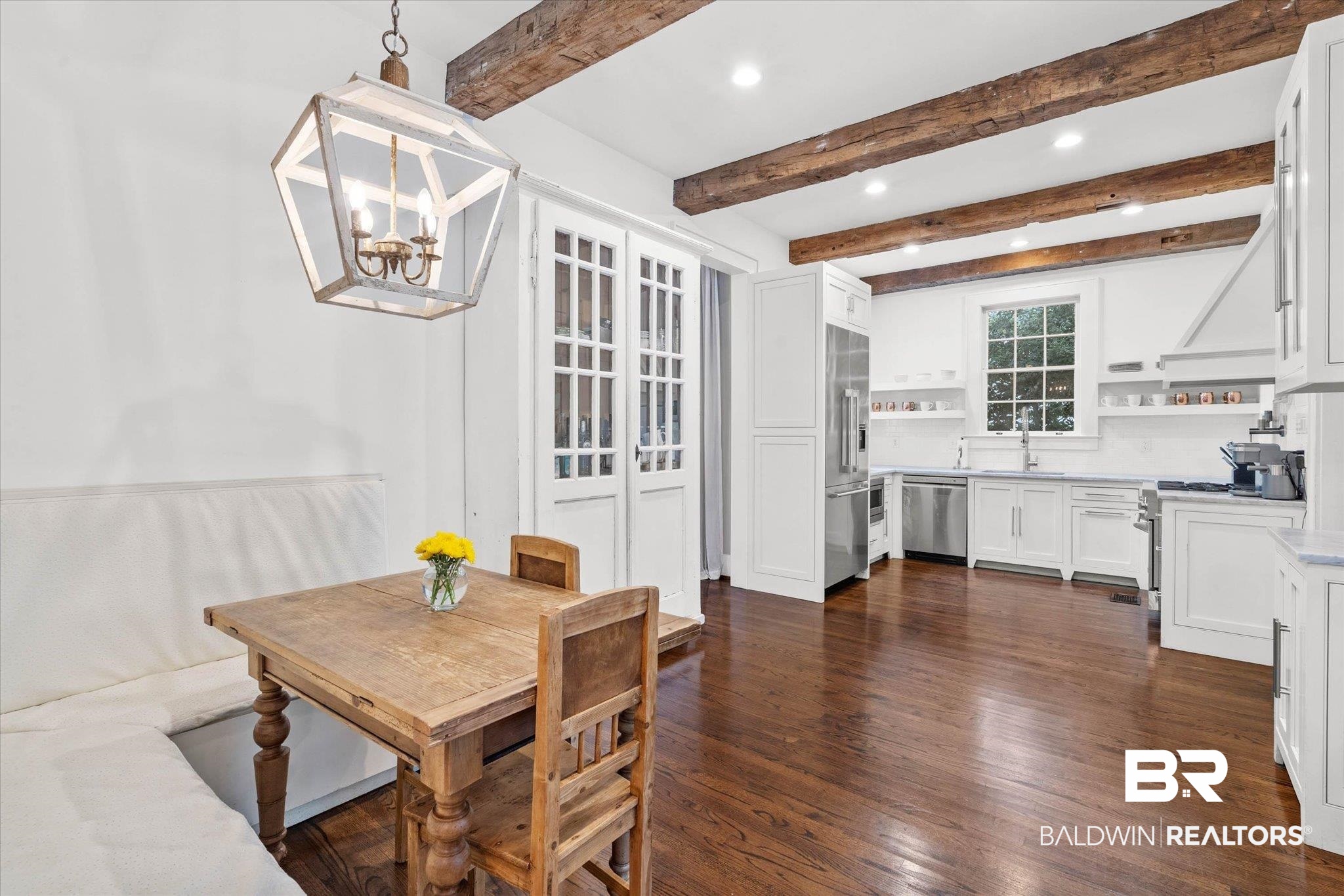 3863 Old Shell Road Mobile, AL 36608 - Photo 9 of 48 Expansive kitchen featuring exposed wood ceiling beams, rich wood-finish flooring, white cabinetry, and stainless steel appliances