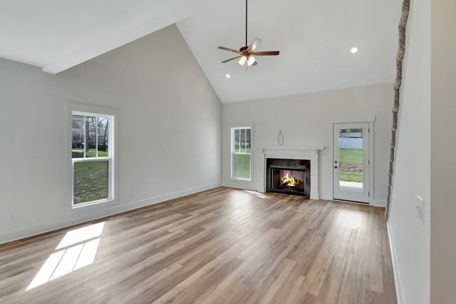 a view of an empty room with wooden floor fireplace and a window