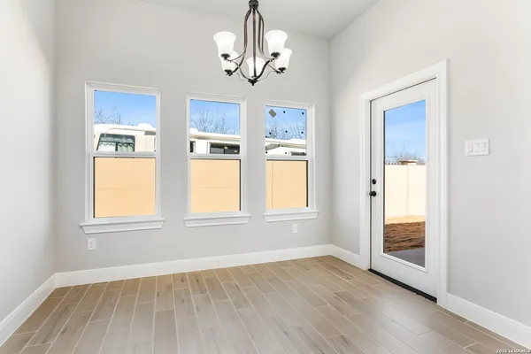 an empty room with wooden floor chandelier and windows