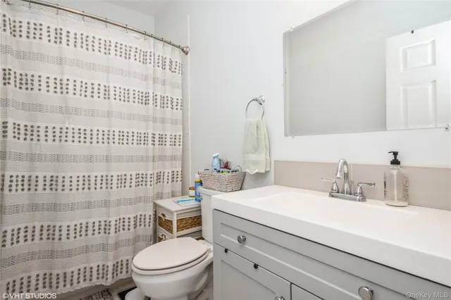 a bathroom with a granite countertop sink a toilet and a mirror