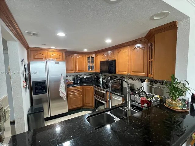 a kitchen with granite countertop a sink stove and cabinets