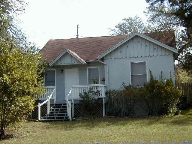 a view of a house with a yard plants and large tree