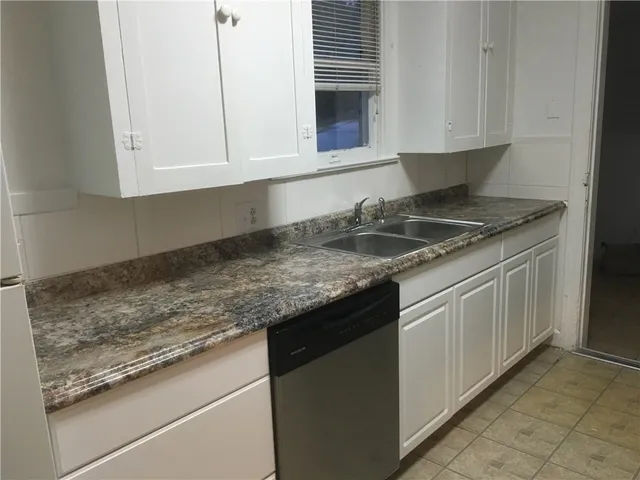 a kitchen with granite countertop white cabinets and a sink
