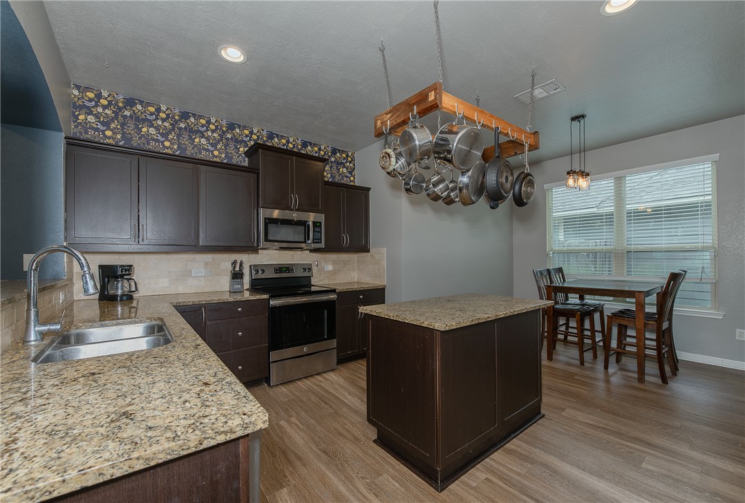 2018 Stubbs Drive Bryan, TX 77807 - Photo 11 of 41 a kitchen with stainless steel appliances granite countertop a stove top oven a sink dishwasher a dining table and chairs with wooden floor