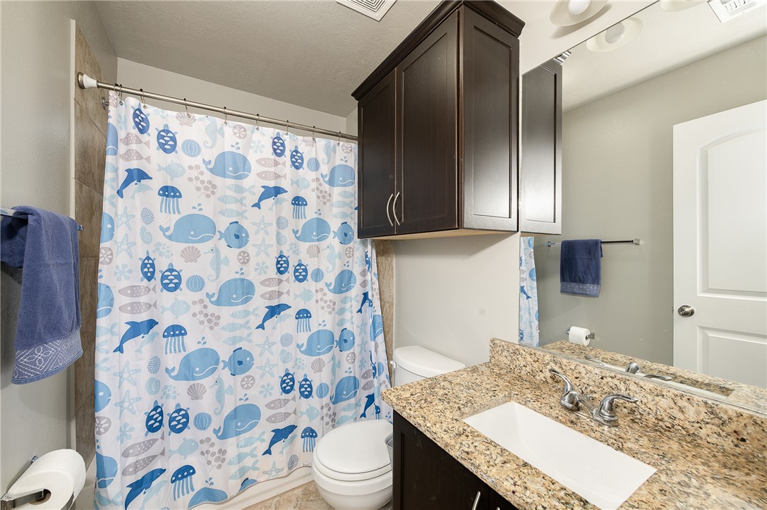 2018 Stubbs Drive Bryan, TX 77807 - Photo 34 of 41 a bathroom with a granite countertop sink toilet a mirror and shower curtain