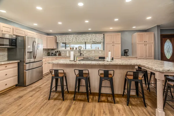 a kitchen with stainless steel appliances granite countertop a kitchen island hardwood floor and a sink