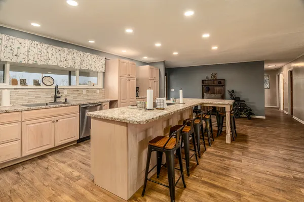a large kitchen with kitchen island a dining table chairs and white cabinets next to a window