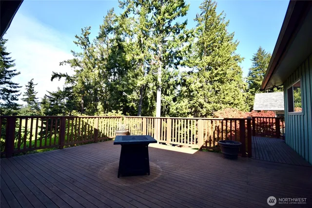 a view of deck with two large trees and wooden fence